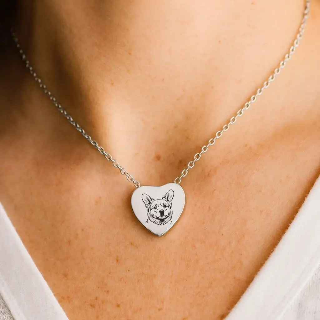 Collana a forma di cuore in argento con incisione del volto di un cane, indossata vicino al collo come ricordo commemorativo di un animale amato.